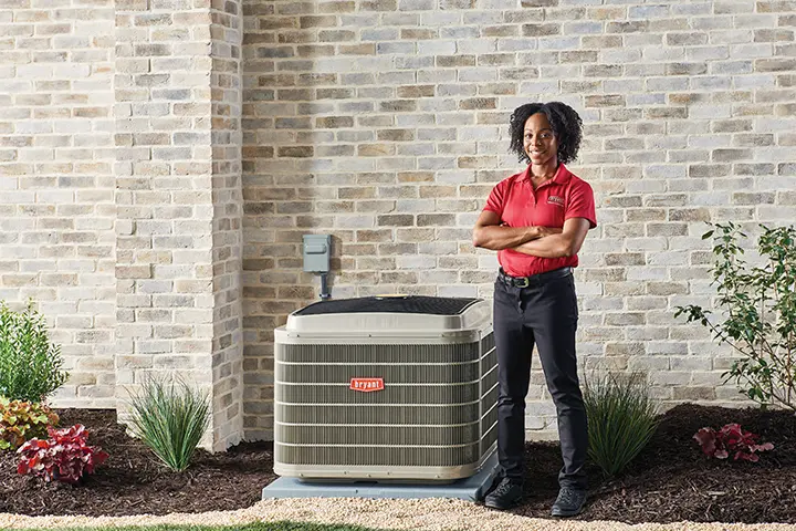 Woman in a Bryant uniform next to an AC system